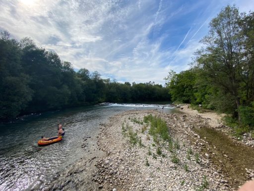 Ein Kanu auf einem ruhigen Fluss, umgeben von grüner Ufervegetation.