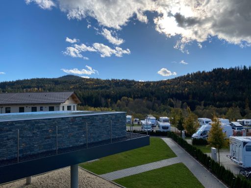 Blick auf eine Landschaft mit Bergen und Wohnmobilen unter einem blauen Himmel.