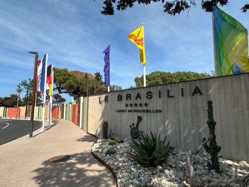 Eingang zu Brasília mit Flaggen und moderner Architektur, umgeben von Pflanzen.