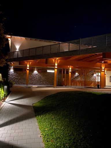 Moderne Gebäude bei Nacht mit beleuchteter Veranda und begrüntem Garten.