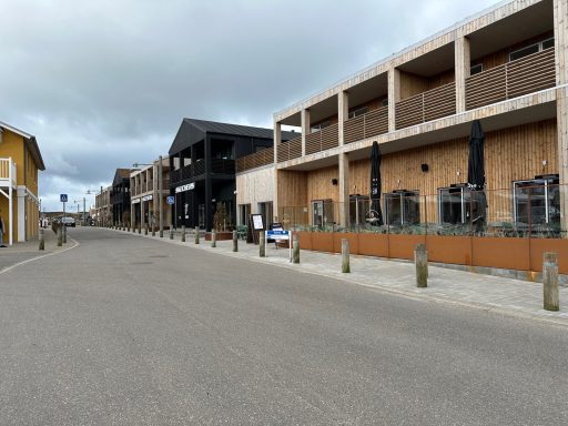 Moderne Gebäude entlang einer ruhigen Straße mit Terrassen und Sitzplätzen.
